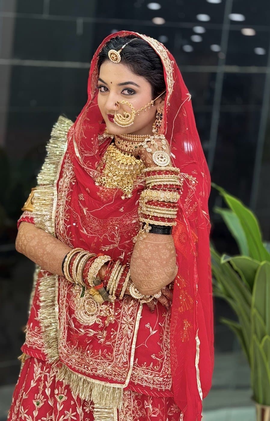 Bride in red and gold traditional outfit holding her dupatta